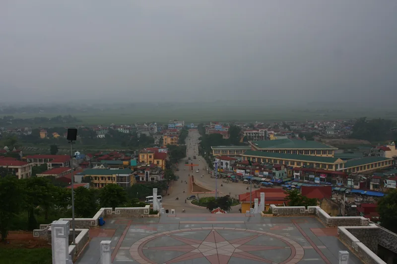 Toàn cảnh thị trấn Điện Biên nhìn từ trên cao dưới bầu trời xám mờ sương, những nóc nhà trải dài đến cánh đồng xanh.