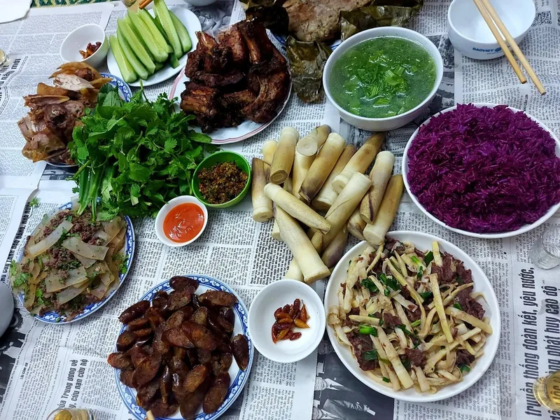 Mâm cỗ truyền thống ở Điện Biên với sườn nướng, rau thơm, măng, xôi tím và các loại nước chấm trải trên báo.